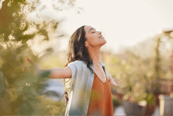 Woman with vibrant hair enjoying sunlight outdoors.