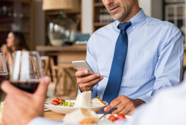 A man in a dress shirt looks at his phone, looking to increase his energy by intermittent fasting.