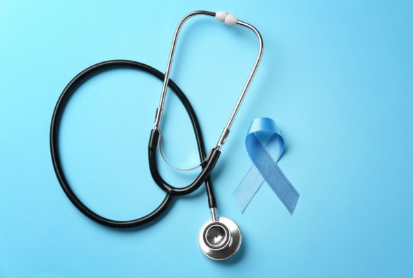 A blue ribbon and stethoscope on a blue background, reminding people to get cancer screening tests.