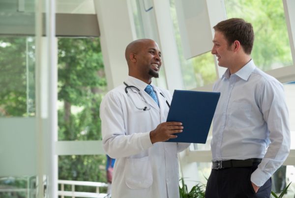 A male member talks to his private physician in the lobby of his concierge medical practice.