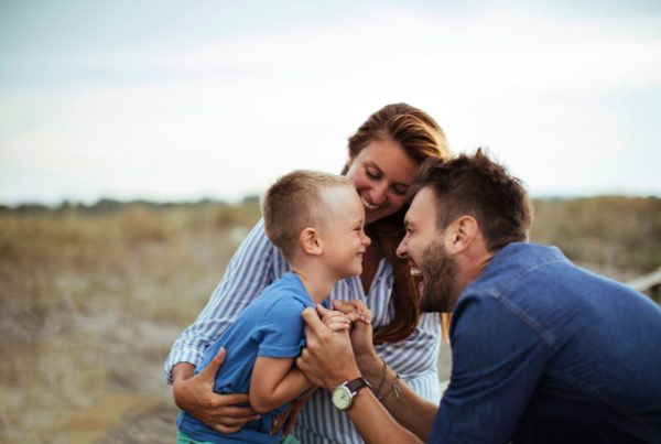 Two parents hold their son in an embrace, laughing, and celebrating him.