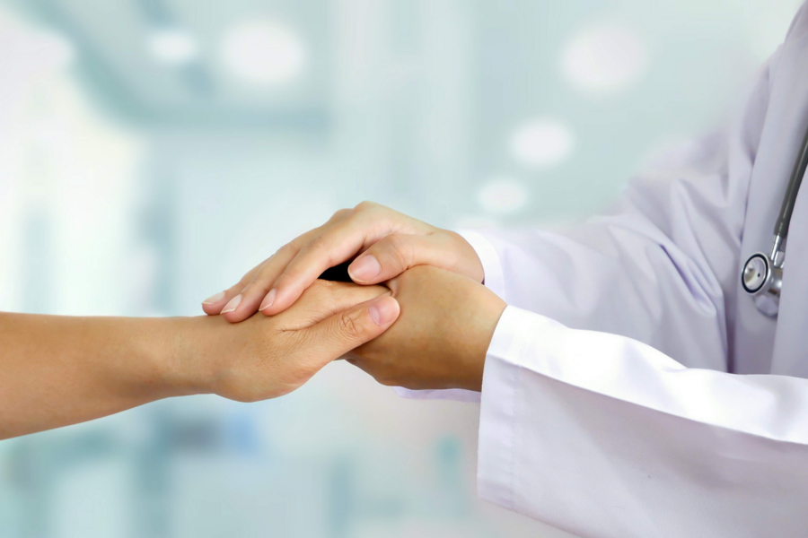 A doctor at a concierge medicine practice holds the hand of a patient, showing empathy and personalized care.