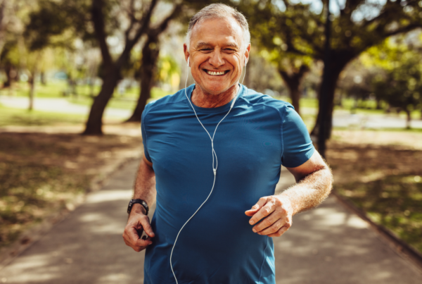 An older man in a blue shirt jogs through the park to help balance his testosterone levels.