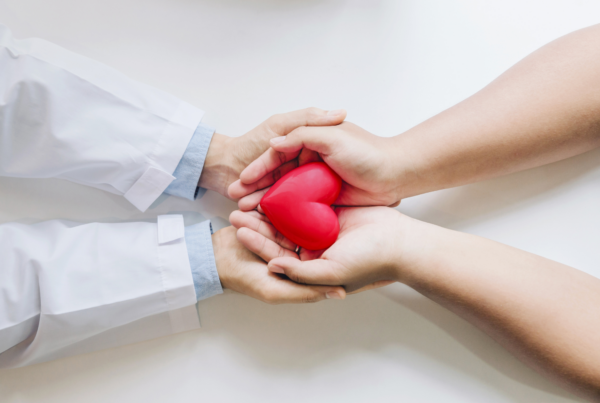 A doctor and patient's hands cradling a heart representing self advocacy in the doctor-patient relationship.