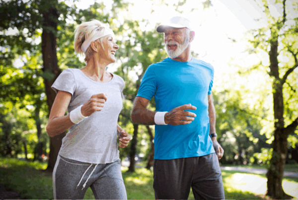 Active senior couple jogging in park at moderate pace.
