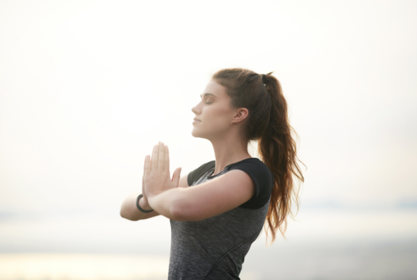 Woman practicing mindfulness with hands together, symbolizing how a positive mindset can enhance long-term health.