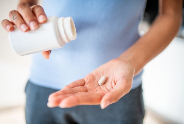 A close-up of a person holding a white tablet in their hand, illustrating caution when taking medications.