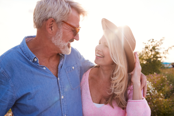 Joyful man and woman embracing each other at sunset while smiling, symbolizing vitality, longevity, and well-being.