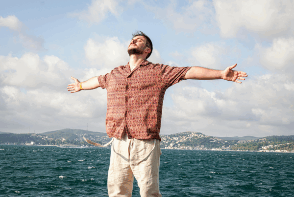 Middle-aged man with arms outstretched in joy and confidence against vibrant sky.