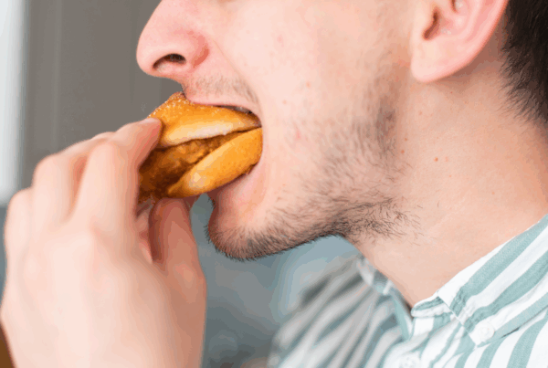 Close-up of man biting into burger.
