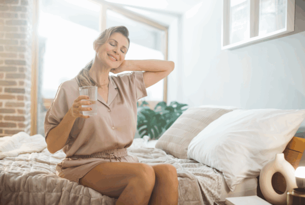 Smiling middle-aged woman in casual clothing sitting on bed.