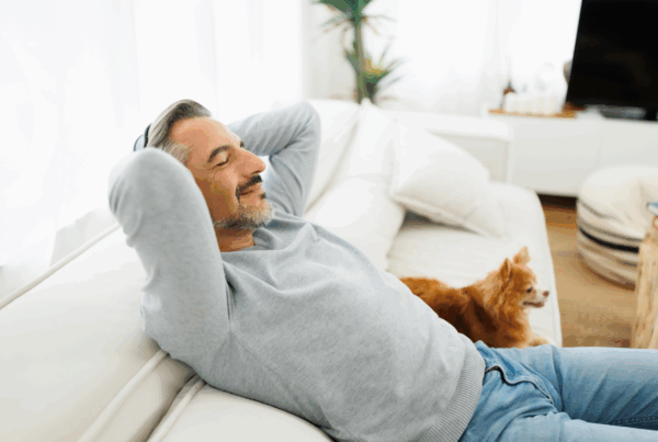 Middle-aged man relaxing on couch with dog.