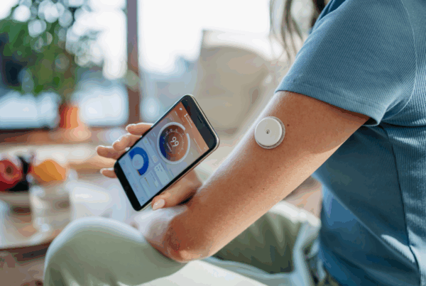 Close-up of person's arm with continuous glucose monitor showing blood sugar reading.