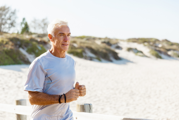 Fit middle-aged man jogging on beach.