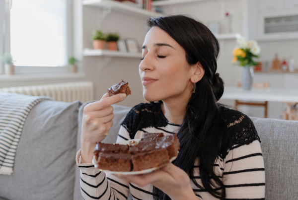 Woman sitting on a couch savoring a piece of chocolate cake.