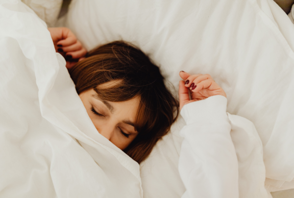Woman sleeping peacefully nestled in white bedding.