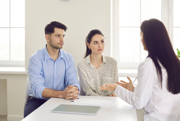 A couple listens attentively as a physician explains information during a serious medical consultation after a cancer diagnosis.