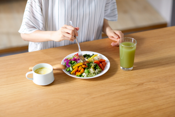 A person eats a colorful vegetable bowl with a green juice beside it, reflecting common nutrition myths.