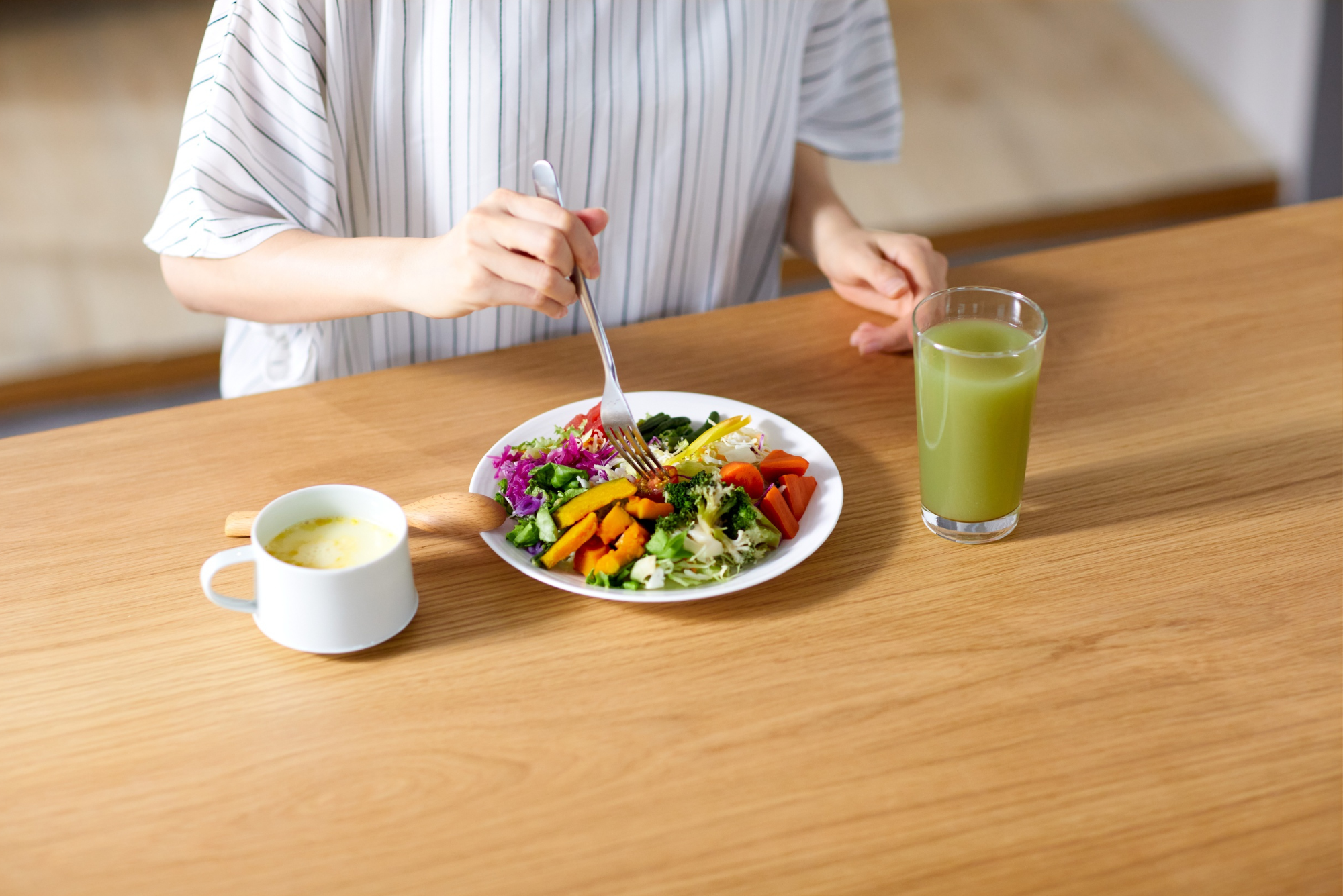 A person eats a colorful vegetable bowl with a green juice beside it, reflecting common nutrition myths.