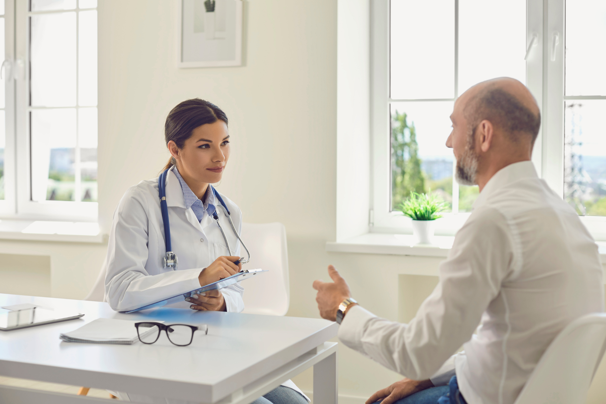 Female doctor listening to a male patient during a medical consultation about cancer screening and prevention.